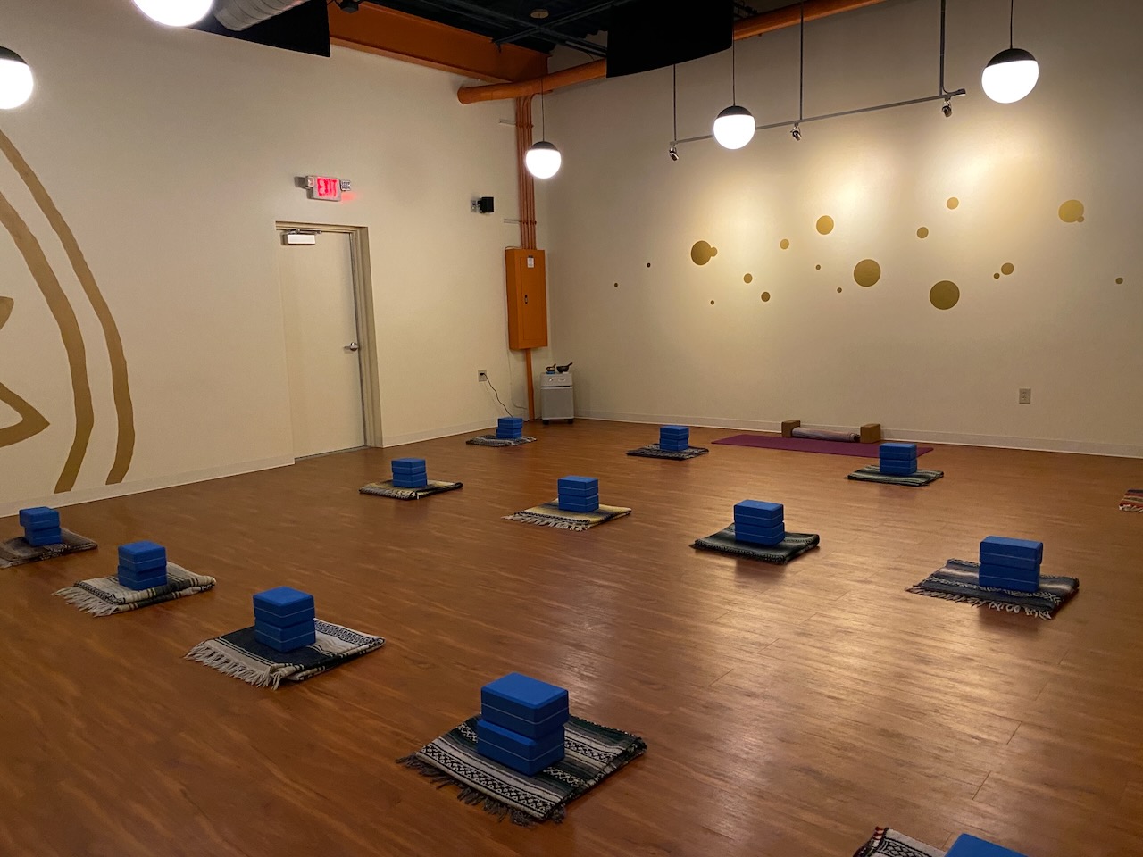 A yoga studio with props set up in stations, waiting for students to lay down their mats